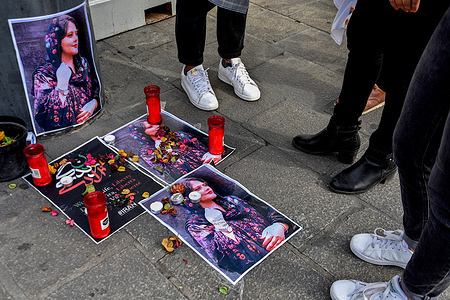 Participants gather around Mahsa Amini's photos to pay tribute to the young woman. People are paying tribute to Mahsa Amini, a 22-year-old Iranian girl who was arrested and detained by Iranian vice police for wearing a veil improperly that made her dress indecent in the eyes of the authorities, she died after three days in a coma.