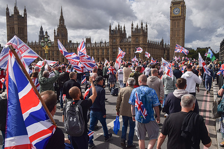 Protesters march with Union Jacks and English flags on Westminster Bridge past the Houses of Parliament during the 'Unite The Kingdom' demonstration. Right-wing protesters marched to Westminster and staged a rally against immigration and the government outside Downing Street, organised by far-right activist Tommy Robinson, whose real name is Stephen Yaxley-Lennon.