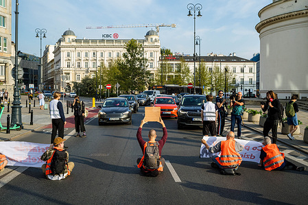 Climate protestors sit in the road to block traffic. On the morning of the 5th September, a group of activists from Ostatnie Pokolenie (the Last Generation) block the road beneath St. Alexander's Church on Warsaw's Three Crosses Square. The action is one of many designed to advocate for cheaper and wider public transport options. The group are demanding that the government shifts 100% of the money allocated for new expressways to regional public transport, and introduces a low-cost, 50PLN ticket for public transport throughout Poland. The series of road blocks take place on the week that Polish students return to school. "People must demand change" they state, "otherwise the government will continue to disregard our basic safety."
