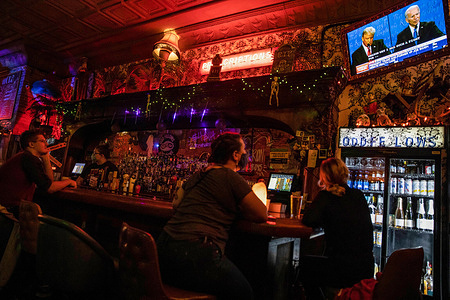 People seen watching Donald Trump and Joe Biden speak on a Tv screen at Oddfellows Liquor Bar during the final presidential debate.