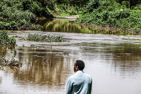 A man stands next to a flooded road after Njoro River in Nakuru County broke its banks following heavy rainfall being experienced in Kenya. The Kenya Meteorological Department predicts that the rain will continue in several parts of the country.