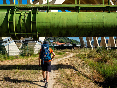 A pilgrim walks under a big pipe outside of Lisbon.
The Camino de Santiago (the Way of St. James) is a large network of ancient pilgrim routes stretching across Europe and coming together at the tomb of St. James (Santiago in Spanish) in Santiago de Compostela in north-west Spain. Yearly, thousands of people of various backgrounds walk the Camino de Santiago either on their own or in organized groups.