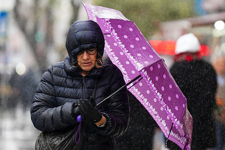 A woman holds an umbrella, while walking along the street during a rainy day in Istanbul.
