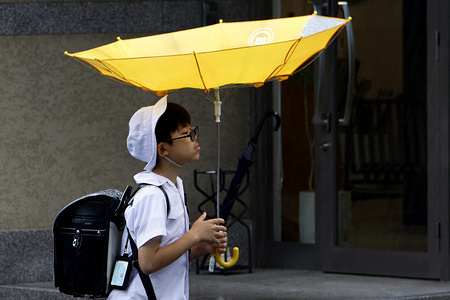 A schoolboy walks through strong winds with an umbrella turned inside out as a typhoon makes a direct hit on Tokyo's Shinjuku district. Typhoon Mekkhala (Typhoon No. 7 in Japan) brought heavy rain and strong winds to Tokyo, while a trailing system, Typhoon Higos (Typhoon No. 8), interacted with the seasonal rain front over mainland Japan. The combined weather systems produced torrential rainfall and severe gales, resulting in record-breaking June precipitation in parts of the country.