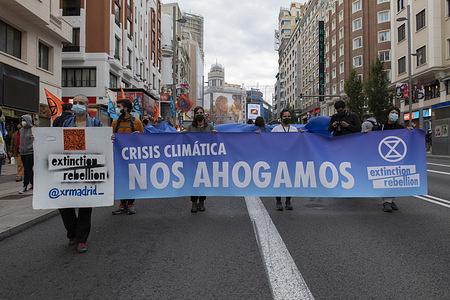 Activists wearing face masks hold a banner saying "Climate Crisis, we sink" during the demonstration.
During the third international rebellion, The Extinction Rebellion movement blocked Gran Vía Street in Madrid to protest against the consequences of rising sea levels. The movement, carrying a 150 square meters blue cloth from Callao Square to Spain square, marched across Gran Vía Street to make visible the growing number of people affected by the rise in sea level, caused by climate change. This act, under the name "We sink" has represented the huge number of deaths due to the rise in sea level.