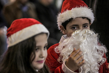 Palestinian children dressed as Santa Claus attend a Christmas tree lighting ceremony in Gaza City. The event was organized by the non-governmental organization NGO Young Men's Christian Association (YMCA).