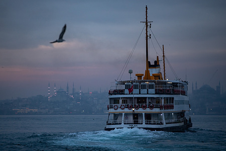 A city ferry Is seen in Istanbul at sunset, with the Hagia Sophia and Sultanahmet mosques in the background.