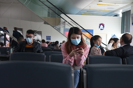 A woman wearing a face mask as a precaution to the outbreak of Coronavirus looks at her phone at the departure terminal of Zhuhai airport.
The World Health Organisation (W.H.O) has declared the epidemic an international public health emergency.