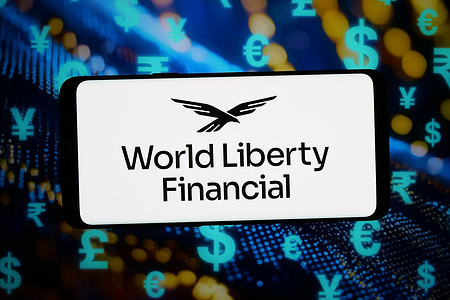 In this photo illustration, the crypto company World Liberty Financial (WLFI) logo is seen displayed on a smartphone in front of an abstract background on a computer screen.