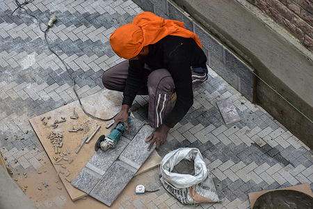 A laborer cuts tiles to be installed at a construction project on International Labour Day in Srinagar. International Labour Day also known as May Day is marked across the world on May 1.The International Labour Day commemorates the historic struggle of working people throughout the world.