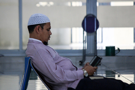 An Aceh Muslim Ummah reads the Qur'an on a smartphone while waiting to breaking the fast during Ramadan at the Baiturrahman Mosque.
In Indonesia, with the world's largest Muslim population, mainstream Islamic organisations have issued religious pronouncements asking Muslims not to hold mass prayers or to have communal dinners known as iftar to end daily fasts at sunset.