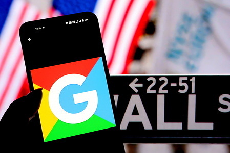 In this photo illustration, a Google Logo seen displayed on a smartphone with the Wall Street - New York Stock Exchange logo in the background.
