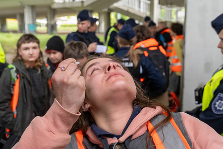 An activist reacts after having been sprayed in the face with pepper spray by a driver during a blockade by the Last Generation (Ostatnie Pokolenie) group. Fifteen individuals from the activist group "Ostatnie Pokolenie" ("Last Generation") staged a traffic blockade on Grota-Roweckiego Bridge marking the fifth consecutive day of similar actions across the city. Demonstrators glued themselves to the roadway using industrial-strength adhesives temporarily halting vehicle flow and drawing police intervention. The protest aimed to raise awareness of regional transportation issues. Isolated incidents of tension were reported during the event including verbal altercations and a civilian using pepper spray. The group has stated it will continue the campaign throughout May.