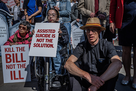 A young girl in a wheelchair protests alongside a priest against the Assisted Dying Bill outside Westminster. Hundreds of campaigners gather to protest against the bill which is currently being amended in the House of Commons. The bill, if passed will permit assisted death for patients with a terminal illness by prescribing life-ending medication.