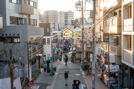 Pedestrians walk along a quiet street in the historic Yanaka neighborhood of Tokyo known for its preserved postwar-era atmosphere. Yanaka is one of Tokyo’s most preserved historic neighborhoods, known for its narrow streets, traditional wooden houses, and quiet temple-lined atmosphere. Unlike much of the modern city, it offers a glimpse into old Tokyo with local shops, artisan crafts, and a slower, more nostalgic pace of life.