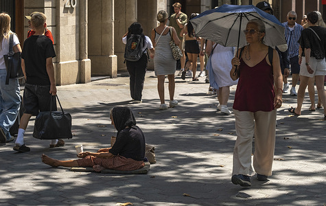 A homeless woman seen begging on Passeig de Gràcia during the high temperatures. The Barcelona coast is under extreme weather alert with high temperatures. The city has been suffering for weeks with high temperatures. The heat is affecting the health of residents, harassing tourism and exhausting the homeless.