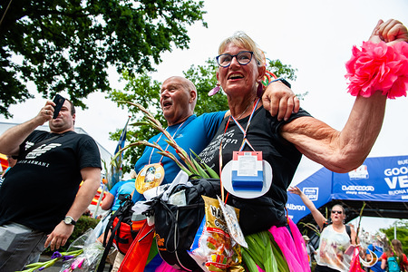A couple arrives at the finish line during the last day.
Since it is the world’s biggest multi-day walking event, the Four Days March is seen as the prime example of sportsmanship and international bonding between military servicemen and women and civilians from many different countries. This year marks the 75th anniversary of the pontoon bridge that has been set up each year temporarily over the River Meuse at Cuijk. The final kilometers are at the Via Gladiola Street, where as tradition every participant carries gladiolus plants and are welcomed by relatives and partners.