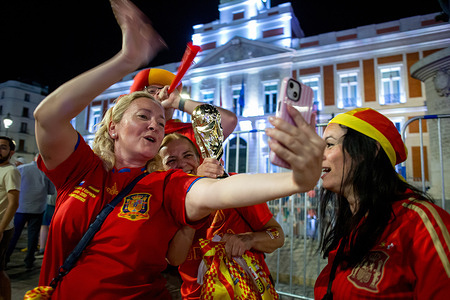 Fans hold a replica of the World Cup trophy while recording a video in Puerta del Sol during the celebrations following Spain's victory in the FIFA World Cup final against Argentina. Spain beat Argentina 1-0 after extra time.