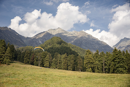 A paraglider is seen soaring above the hills on a sunny autumn day in Pahalgam. Pahalgam, also called the “Valley of Shepherds,” is a peaceful town in the heart of Kashmir. The Lidder River flows through its green pine forests and snow-covered mountains, making it one of the most beautiful places in the valley.