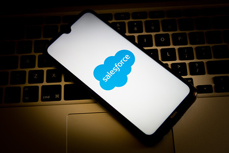 In this photo illustration, a Salesforce logo seen displayed on a smartphone screen with a computer keyboard in the background.
