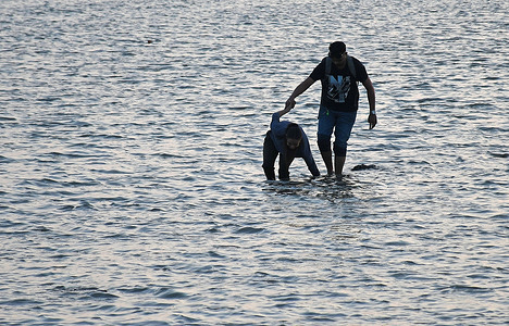 A woman loses balance in the water as a man tries to hold her at a beach in Mumbai.