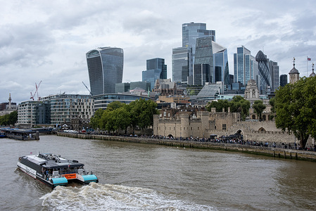 An Uber Boat passes by the Tower of London and the financial district in London. London is a very popular tourist destination because of the museums, galleries and the historical buildings on the both banks of the River Thames.