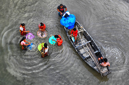 Fishing family seen using colourful nets during fishing on the Matla river. Most inhabitants of the delta are fishermen who are facing challenges as the ocean swallows up land in the world's largest mangrove forest, humans and tigers are being squeezed into an ever-shrinking space in the Indian Sundarbans with deadly consequences. The sea level has risen by an average of 3 - 5 centimeters a year over the past two decades in the Sundarbans leading to one of the fastest rates of coastal erosion in the world.
