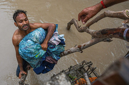 A man struggles to climb to a bridge with his belongings after being displaced by rising water levels in the Yamuna River following heavy monsoon rains in New Delhi. The Yamuna river water level in Delhi reached an all-time high of 207.55 meters. The government warned of flood-like conditions and asked residents of the riverbanks and low-lying areas to evacuate their homes.