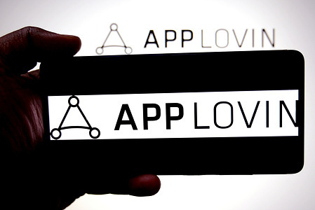In this photo illustration, an AppLovin logo is seen displayed on a smartphone and in the background.