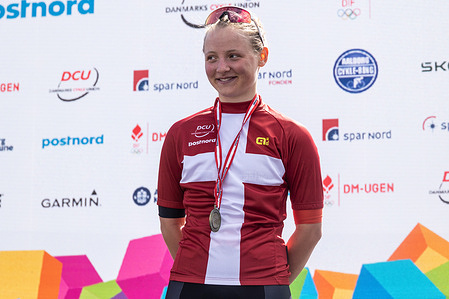 Gold medalist Ida Dam Fialla of Team Nyt Syn by Fialla - U19P is seen on the podium during the medal ceremony after the Women's U19 Road Race at the Danish Championship 2025. When DM Week returns to Aalborg from 23-29 June 2025, there will be more sports than ever before, new disciplines on the program and an entire city in motion. During an intense week, some of Denmark's most talented athletes will compete for DM gold in over 120 disciplines - from classics like cycling and swimming to high diving from the Limfjord Bridge, dance, speedway and 3x3 basketball. This will be the fourth time DM Week has been held, and the third time Aalborg has hosted it.