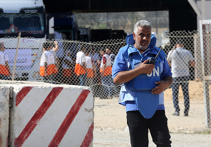 A Palestinian worker from UN receives the humanitarian aid brought by first convoy of relief trucks from Egyptian side, at Rafah border. United Nations (UN) agences are expected to deliver humanitarian aid to those in need in various areas of the Gaza Strip, Gaza government media office said on Saturday.
