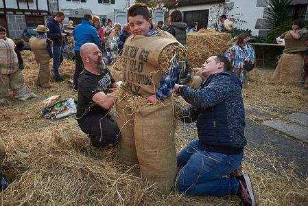 A child disguised as "zaku-zaharrak" the men of the old sack stuffed with straw, is prepared by men during the carnival of Lesaka. The "zaku-zaharrak" are typical characters of the Lesaka carnival, stuffed into sacks full of straw with their faces covered by scarves, who carry inflated bladders to hit the people who walk the streets of the town at sunset.