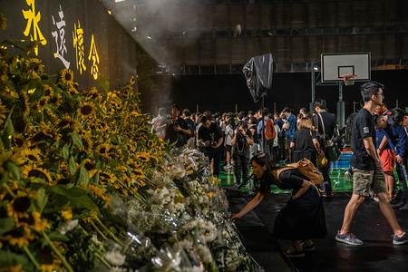 A woman places flower on stage to pay his respect during a memorial service for Marco Leung.
A memorial service was held by public for Marco Leung, a political activist who plunged to death while protesting against the controversial extradition bill on 15 June 2019.