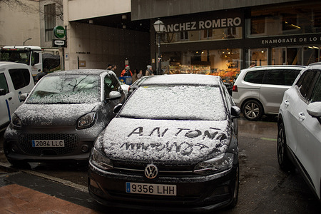 A couple of cars covered in snow are seen along the street in the center of Madrid. The rain and snow that continued until midday, causing closures on some roads in the north of the city.