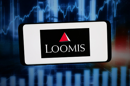 In this photo illustration, the logo of Swedish cash handling company Loomis AB is displayed on a smartphone in front of abstract background on computer screen.