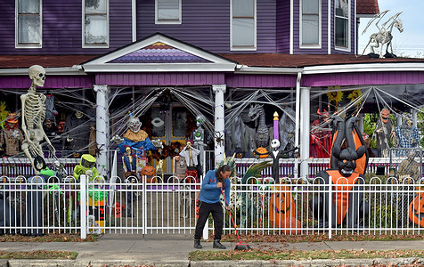 A man sweeps his sidewalk outside his very decorated Halloween home on the Main Street in Berwick.