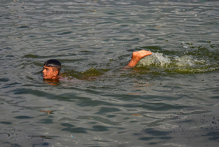 A man cools off in a lake during a hot summer day in Srinagar.