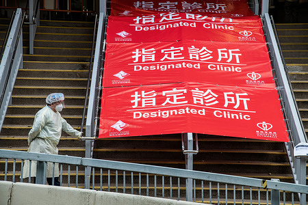 A health care worker awaits visitors to the designated COVID-19 clinic in Shau Kei Wan. In response to the exponential rise in COVID-19 cases that are overloading Hong Kong's hospitals, the government has set up designated clinics across the city to handle those who test positive. The clinics are intended to treat those with mild symptoms, with daily quotas established and a soon-to-be launched taxi transport program. Hong Kong is currently in the fifth phase of the pandemic, recording thousands of new cases per day.