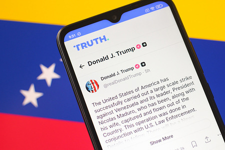 In this photo illustration, a smartphone displays a Truth Social post by U.S. President Donald J. Trump claiming that Venezuelan President Nicolás Maduro and his wife Cilia Flores were captured and flown out of Venezuela, with the Venezuelan national flag seen in the background.