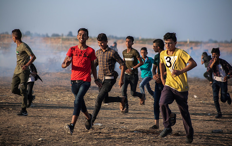 Palestinian demonstrators take cover from tear gas smoke canisters fired at them during the clashes.
Palestinians clash with the Israeli forces during a protest calling for lifting the Israeli siege on Gaza and demanding for the right to return to their homeland, at the Israel-Gaza border fence in the southern Gaza Strip.