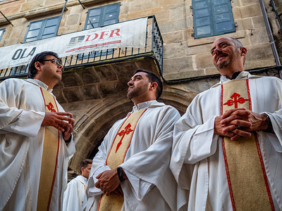 Three priests are seen talking while the procession is stopped. Hundreds of locals, tourists, and pilgrims attended the celebration of Corpus Christi, which included a Mass on the street. At the end of the procession, benediction of the Blessed Sacrament was imparted.