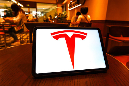 In this photo illustration, the Tesla logo is seen displayed on the screen of the tablet.