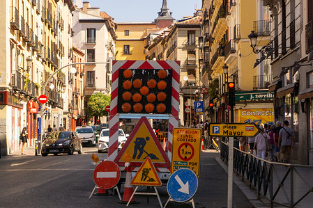 Several signs indicate construction work is underway on a street in central Madrid.
