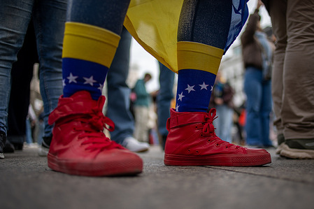 A protester wears socks and shoes in the colors of the Venezuelan flag during the rally. Venezuelan dissidents residing in Madrid gathered to celebrate the US attacks in Caracas, Venezuela, and the subsequent arrest of Nicolás Maduro and his wife by US forces.