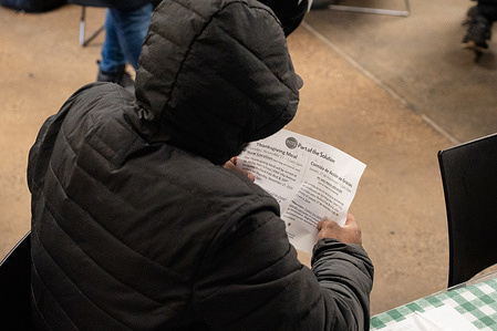 A member of the community reads details of the Thanksgiving meal during service at the Part Of The Solution (POTS) food pantry and community center in the Fordham neighborhood of the Bronx borough in New York City. As federal food aid declines, Mamdani has reaffirmed his administration’s commitment to lowering food costs.