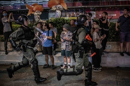 Residents of Mong Kok area observe a group of riot police chasing demonstrators on Nathan Road during the protests.
After 14 weeks of protests, demonstrations have continued across Hong Kong despite the withdrawal by Chief Executive, Carrie Lam of a controversial extradition bill. Protests keep taking the streets as demonstrators demands the city’s government to attend to their demands, including an independent inquiry into police brutality, the retraction of the word 'riot' to describe the rallies, and the right for Hong Kong people to vote for their own leaders.