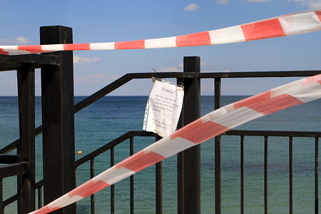 View of a prohibition tape and a sign saying that visiting the Kurortny beach is prohibited. Beaches of Odessa during the war between Russia and Ukraine. Due to the possible landing of the Russian troops, the armed forces of Ukraine mined the beaches and water of the Black Sea. Free access to beaches for the public is strictly prohibited.