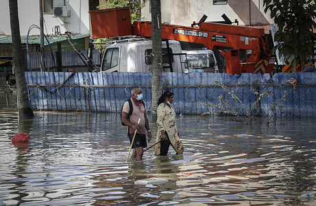 Residents are seen wading through a road in water during the massive floods in the outskirts of Shah Alam.
The three days of torrential rain over the weekend have caused massive flooding, at least 14 dead and others are displaced.