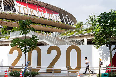 A jogger runs past a large Tokyo 2020 sign around the National Olympic stadium, Gaiemmae.
The Tokyo Olympic Organizing committee are planning to open the delayed Games on July 21st despite uncertainty on what measures to take to ensure safety for athletes, spectators and the local population in the continuing COVID-19 pandemic.