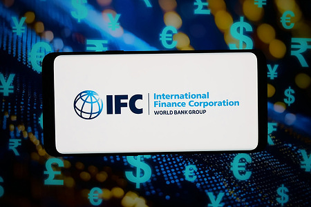In this photo illustration, the logo of International Finance Corporation (IFC) is displayed on a smartphone in front of abstract background on computer screen.